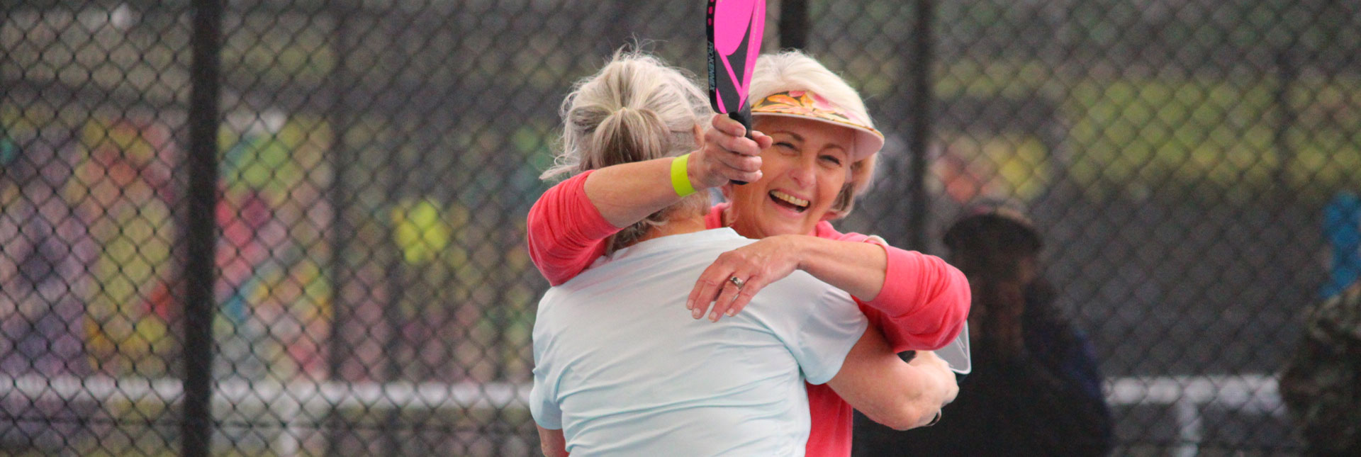 two women hugging after a match of pickleball